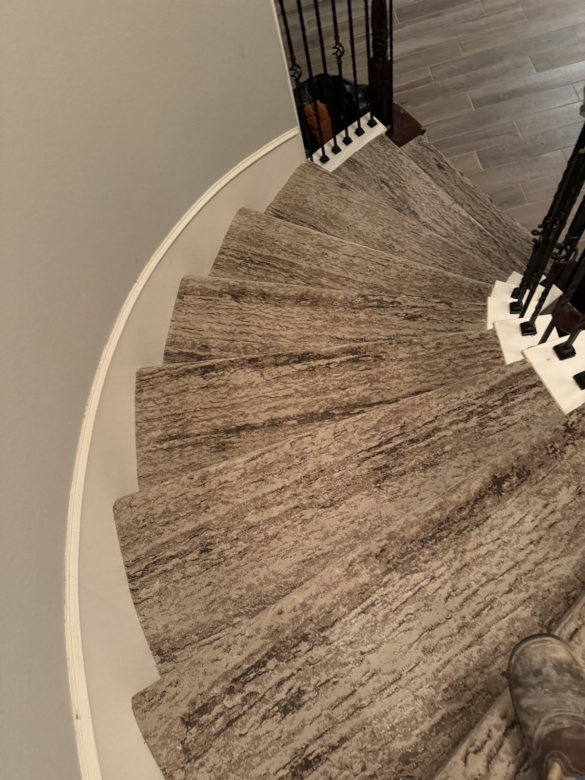 Carpet wrapped around a curved staircase with an iron railing