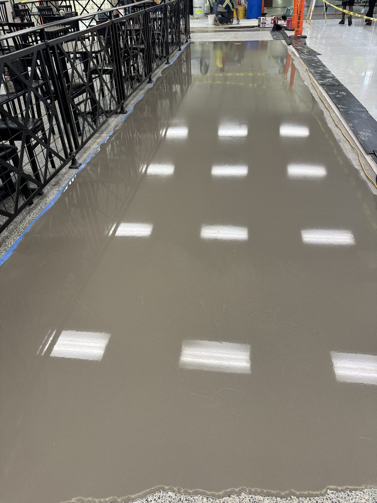 Freshly poured self-leveling underlayment curing to a flat glassy surface in a commercial space