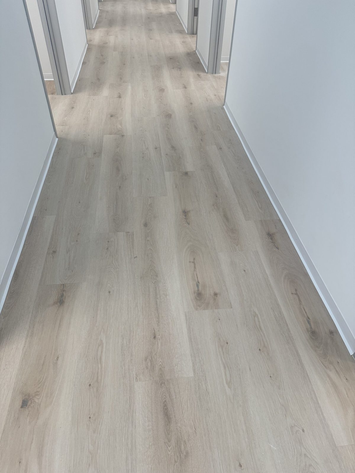 Light white-oak laminate flooring running down a hallway