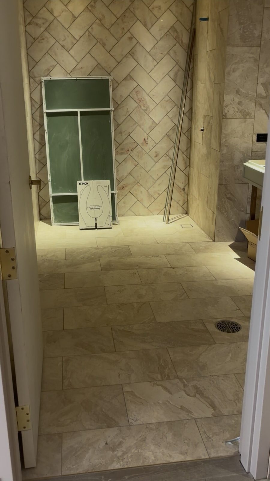 Bathroom with herringbone travertine-look wall tile and large-format stone-look floor tile