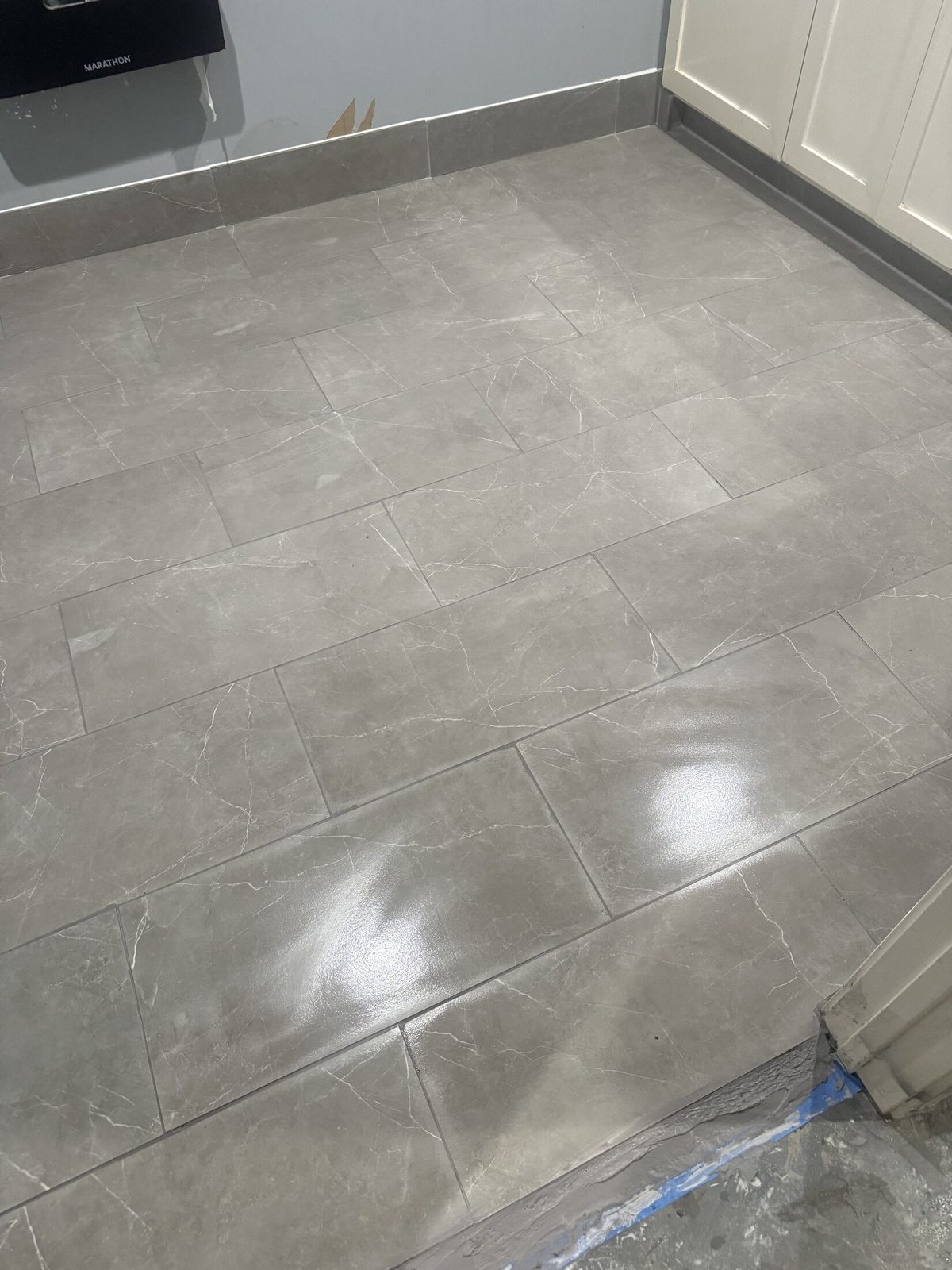 Large-format gray porcelain tile floor with tight, even grout lines